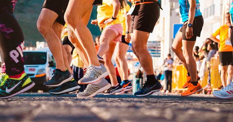 Foto de las piernas de un grupo de personas esperando para correr en una carrera popular.