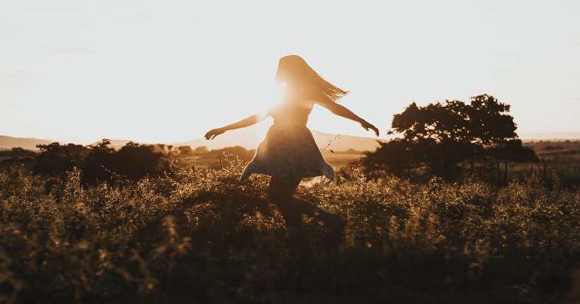 Mujer bailando en el campo a contraluz