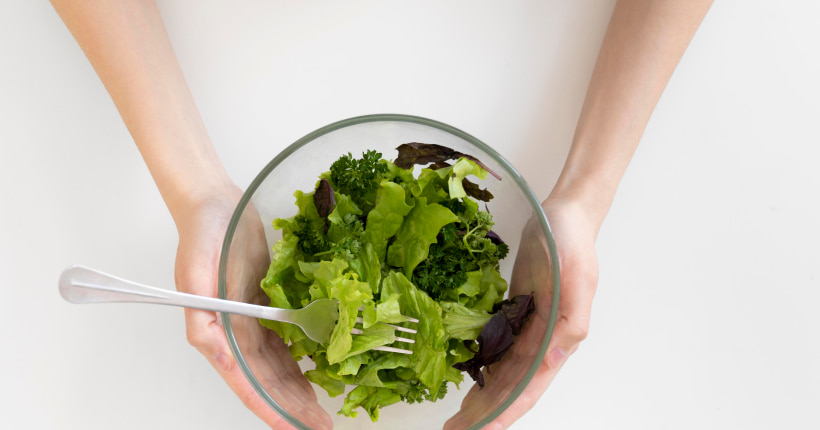 Manos que cogen un bol de ensalada