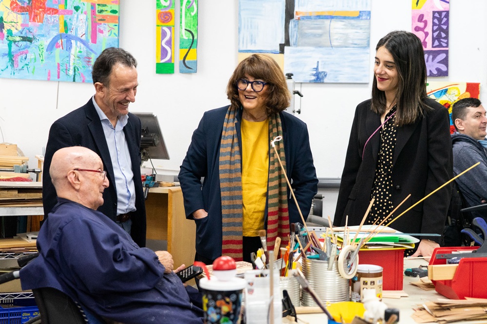 Parte de los asistentes a la visita, junto a usuarios y usuarias del centro, mientras realizan actividades.