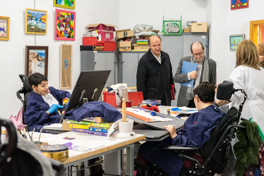 Parte de los asistentes a la visita, junto a usuarios y usuarias del centro, mientras realizan actividades.